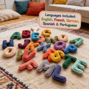 May include: A collection of multi-colored, crocheted alphabet letters scattered across a textured surface. A rectangular sign with a stitched border displays the text: Languages included: English, French, German, Spanish & Portuguese.
