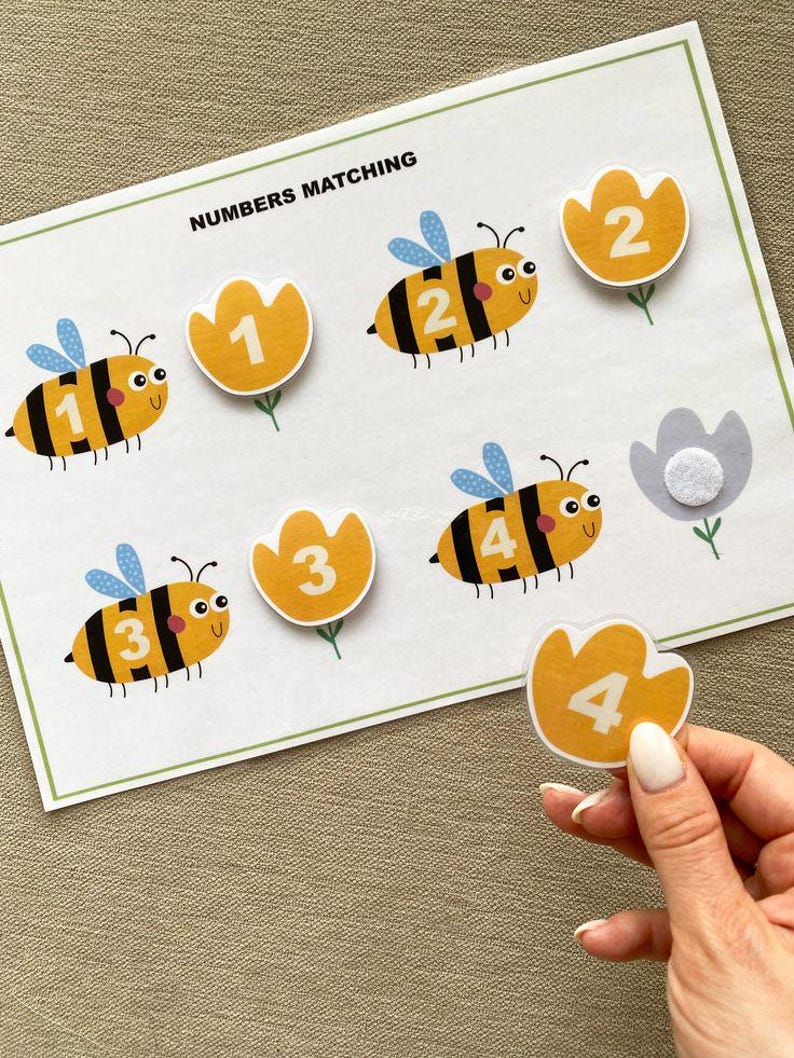 K&ouml;nnte beinhalten: Ein ausdruckbares Zahlen-Zuordnungs-Spiel zum Thema Bienen f&uuml;r Kinder. Das Spiel zeigt vier Bienen mit den Zahlen 1 bis 4 auf ihren K&ouml;rpern und vier gelbe Bl&uuml;tenformen mit den entsprechenden Zahlen. Das Spiel soll Kindern helfen, Zahlen zuzuordnen.