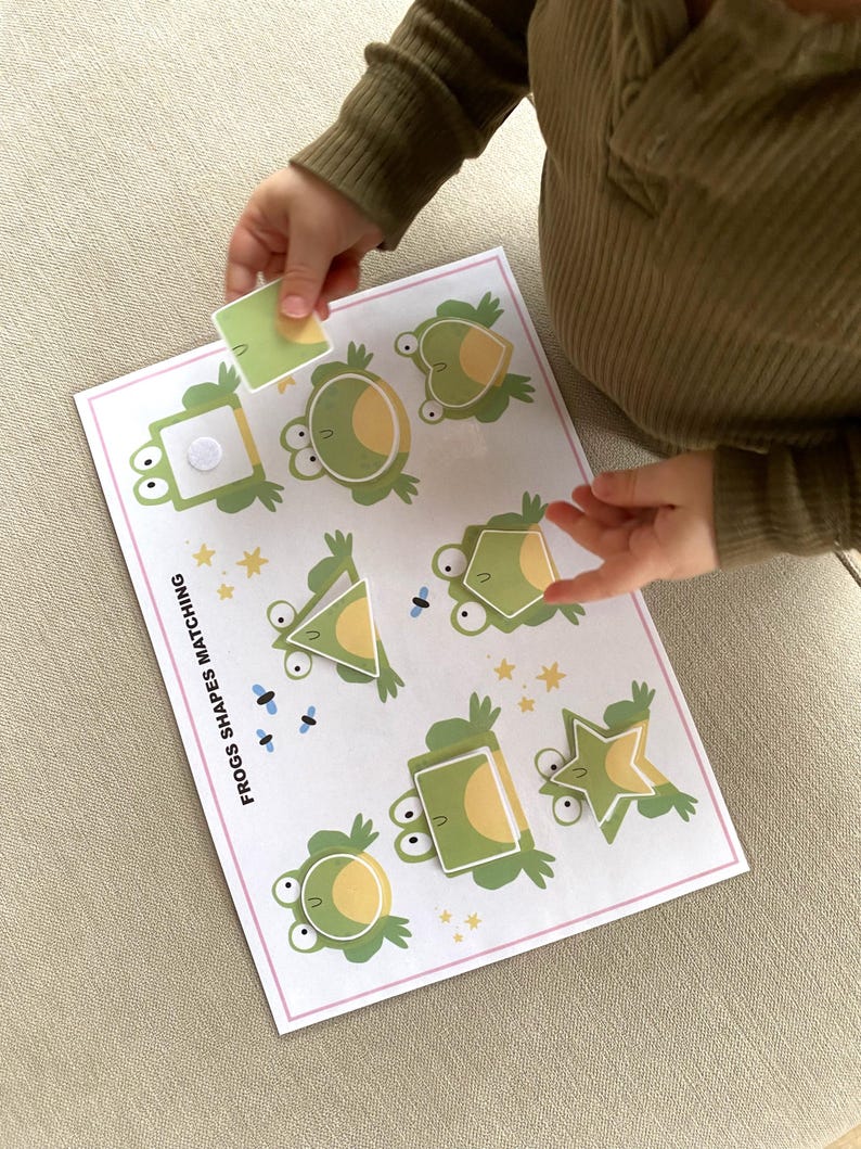 K&ouml;nnte beinhalten: Ein Lernspiel f&uuml;r Kinder mit Fr&ouml;schen in verschiedenen Formen. Das Spiel enth&auml;lt eine Vielzahl von Formen, darunter einen Kreis, ein Quadrat, ein Dreieck und einen Stern. Das Spiel hei&szlig;t "Frogs Shapes Matching".