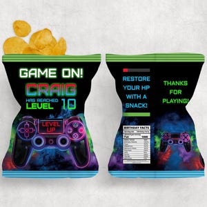 May include: Two black chip bags with a green border. The front of the bag on the left says "Game On! Craig Has Reached Level 10" with a neon blue and pink video game controller. The front of the bag on the right says "Restore Your HP With A Snack! Thanks For Playing!" with a neon blue and pink video game controller.