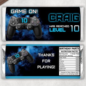 May include: Two chocolate bar wrappers with a gaming theme. The top wrapper says "GAME ON!" and "CRAIG HAS REACHED LEVEL 10". The bottom wrapper says "THANKS FOR PLAYING!" and includes a nutrition facts table.