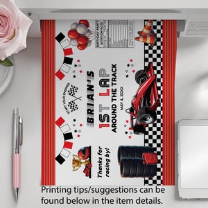 Peut inclure: Une banni&egrave;re de f&ecirc;te imprim&eacute;e sur le th&egrave;me de la course automobile avec une voiture de course rouge, des drapeaux &agrave; damier et le texte "1er tour de Brian autour de la piste". Le design comprend des accents rouges et noirs, des ballons et un troph&eacute;e.