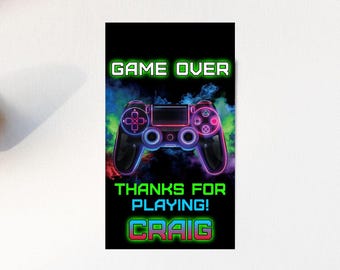May include: A neon green and pink video game controller with the text "GAME OVER" and "THANKS FOR PLAYING! CRAIG" on a black background.