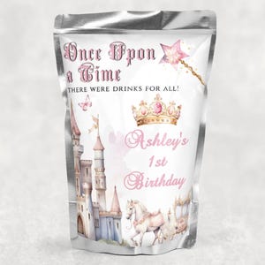 May include: A silver pouch with a pink and blue castle, a white horse pulling a carriage, and a gold crown. The text on the pouch reads "Once Upon a Time" and "Ashley's 1st Birthday".