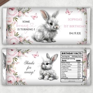 May include: A chocolate bar wrapper with a pink floral design and a white bunny rabbit. The wrapper says "Some bunny is turning 1" and "Sophia's 1st Birthday".