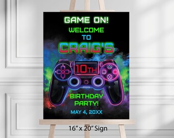May include: A black sign with a neon-style video game controller graphic. Text includes "GAME ON!" and "CRAIG'S 10TH BIRTHDAY PARTY!" The sign is 16 inches by 20 inches.