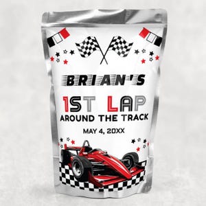 May include: A silver metallic pouch with a racing theme. The pouch features the text "BRIAN'S 1ST LAP AROUND THE TRACK" with a red race car graphic. Checkered flags and stars decorate the design. The date "MAY 4, 20XX" is also included.