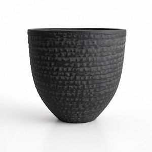 May include: A matte black bowl with a rounded, tapered base and a wide, open top. The exterior surface features a distinct, horizontal, and repetitive textured pattern consisting of small, carved indentations that create a rugged appearance.