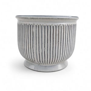 May include: A white ceramic planter with a vertical ribbed texture and a glossy finish. The pot features a wide, flared rim and a circular pedestal base, showcasing a subtle crackle glaze effect throughout the exterior surface of the vessel.