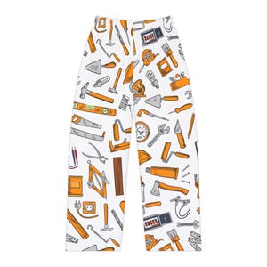 May include: White pajama pants with an all-over pattern of orange and gray tools. The tools include hammers, saws, wrenches, and measuring tapes. The pants have a drawstring waist.