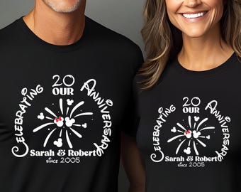 Könnte beinhalten: Zwei schwarze T-Shirts mit weißem Aufdruck zum 20. Jahrestag. Das Design zeigt Feuerwerk, Mickey Mouse Ohren und den Text "Sarah & Robert Seit 2005". Ein lächelndes Paar trägt die Shirts, um ihren Jahrestag zu feiern.