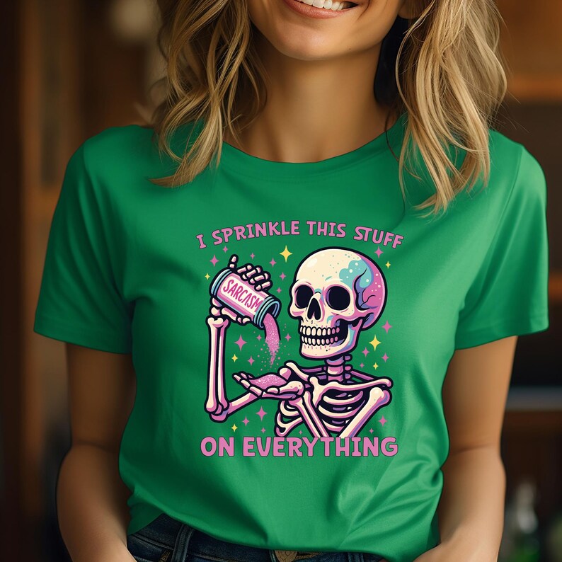 Puede incluir: Camiseta verde con un dise&ntilde;o de esqueleto. El esqueleto est&aacute; rociando "Sarcasmo" de un recipiente. El texto de la camiseta dice: "Lo roc&iacute;o todo."