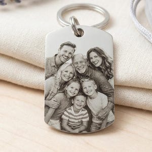 Könnte beinhalten: Ein rechteckiger Schlüsselanhänger aus silberfarbenem Metall mit einem lasergravierten Schwarz-Weiß-Foto einer sechsköpfigen Familie, bestehend aus zwei Erwachsenen und vier Kindern, befestigt an einem runden Metallring.