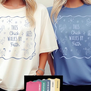 Peut inclure: Deux t-shirts, un ivoire et un bleu, avec le texte "This Chick Walks by Faith" dans un cadre décoratif. Le cadre est orné d'illustrations sur le thème des poulets et de la ferme. Une palette de couleurs de t-shirts supplémentaires est affichée en bas.
