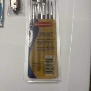 Peut inclure: Un paquet de quatre pinceaux de peinture pour artiste dans un emballage en plastique transparent avec une étiquette jaune et bleue. L'étiquette indique "Rubbermaid Pinceaux d'artiste pour les travaux de précision et les projets d'artisanat".