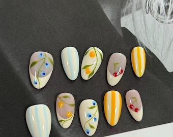 Orchard Picnic: Fruit-inspired press-on nails with cherry, orange, and berry art plus yellow stripe accents – fresh summer nail set.