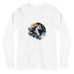 May include: White long-sleeve t-shirt with a circular design featuring a white horse's head with a black mane and tail, surrounded by blue and gold watercolor-like swirls and black and gold dots.