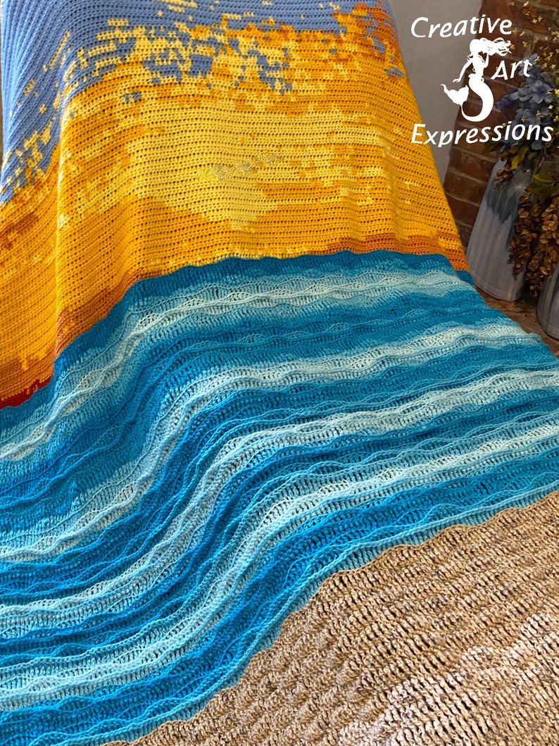 May include: A crocheted blanket with a beach scene. The blanket is made with blue, yellow, and brown yarn. The top of the blanket features a sunset with a blue sky. The middle of the blanket features a blue ocean with waves. The bottom of the blanket features a brown sandy beach.