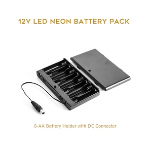 May include: A black 8-AA battery holder with a DC connector and a separate cover. The text "12V LED NEON BATTERY PACK" is at the top. The text "8-AA Battery Holder with DC Connector" is at the bottom.