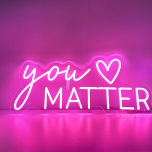 May include: Pink neon sign with the text "you &hearts; matter" in white neon lettering.