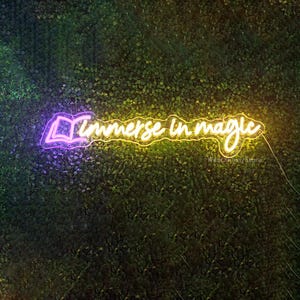 May include: A neon sign with a purple book icon and the words "Immerse in magic" in yellow neon. The sign is mounted on a green wall.