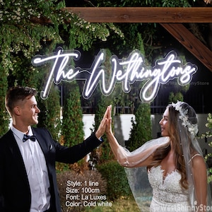 May include: A neon sign in the shape of the words "The Wethingtons" in a cursive font, lit with cold white light. The sign is 100cm in size. The sign is displayed outdoors with a couple in formal attire.