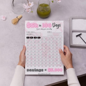 May include: A printable pink and black savings tracker with the text "$5k in 100 Days" and "savings = $5,000". The tracker has 100 squares with numbers in each square. The tracker is designed to help people save money.
