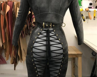 May include: A black leather jacket with a black leather skirt with a lace-up back. The skirt has gold grommets and a black belt with a gold buckle.