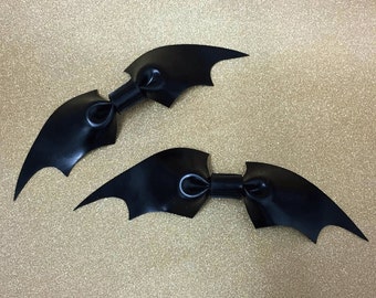 May include: Two black bat-shaped hair clips with a bow in the center of each wing.
