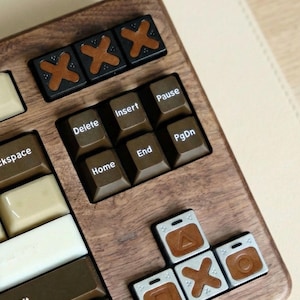 May include: Close-up of a wooden keyboard with custom keycaps. The keycaps are brown, black, and white. Some keycaps have symbols and text, including "Delete", "Insert", "Pause", "PgDn", "Home", and "End".