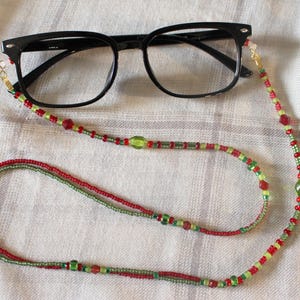May include: A red and green beaded eyeglass chain with a pair of black eyeglasses.