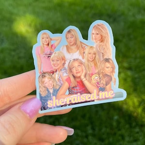 May include: A light blue sticker featuring a collage of images of a blonde woman in various poses. The sticker has the text "she raised me" in a pink and yellow font.