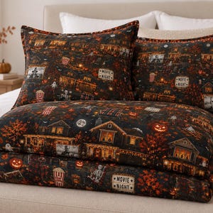 Könnte beinhalten: Ein Bettwäscheset aus dunklem Stoff mit einem wiederkehrenden Halloween-Muster aus Häusern, Kürbissen, Skeletten und Popcorn-Eimern. Das Design enthält Schilder mit der Aufschrift MOVIE NIGHT sowie herbstliche Bäume und einen Vollmond.