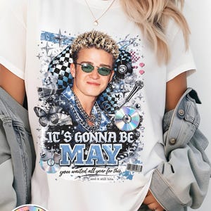 May include: White t-shirt featuring a graphic of a man wearing sunglasses, with the text "IT'S GONNA BE MAY". The design includes a CD, microphone, and butterfly. The shirt has a "90S ERA" logo.