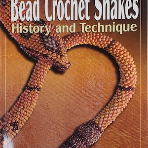 May include: Book cover featuring a beaded snake made with crochet. The book title is "Bead Crochet Snakes: History and Technique" by Adele Rogers Recklies.