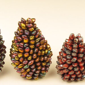 Op de afbeelding: Vier iriserende, kegelvormige ornamenten in verschillende maten, met een kleurovergang van rood, oranje en goud.