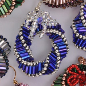May include: A set of six pairs of earrings made with colorful glass beads. The earrings are in the shape of a wreath, a bow, and a spiral. The earrings are all different colors, including red, green, blue, silver, and pink.