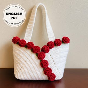 Könnte beinhalten: Weiße gehäkelte Tragetasche mit roten gehäkelten Rosen am oberen Rand. Die Tasche hat ein Etikett für den digitalen Musterdownload mit dem Text "Digitales Muster Englisch PDF Sofort-Download".