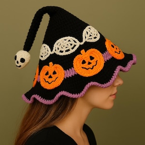 Puede incluir: Sombrero de bruja de Halloween de ganchillo negro con aplicaciones de calabazas naranjas, una calavera blanca al final de la punta del sombrero y un borde morado festoneado. El sombrero tiene un diseño de encaje blanco.