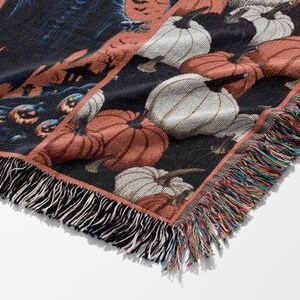 May include: Woven Halloween throw blanket featuring a repeating pattern of pumpkins in shades of orange and white against a black background. The blanket has a fringed edge with multiple colors. The design includes a spooky scene.