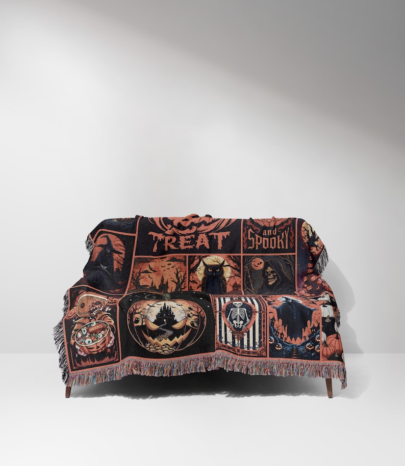 May include: A black and orange Halloween-themed throw blanket draped over a couch. The blanket features various spooky illustrations, including a pumpkin, a skeleton, and a black cat. The words "TREAT and SPOOKY" are also visible on the blanket.