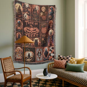May include: A Halloween-themed throw blanket with a grid pattern featuring spooky illustrations and the words "Trick or Treat" and "Sweet and Spooky". The blanket is displayed on a wall in a room with a chair, couch, and checkered rug.