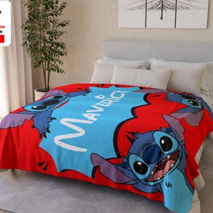 Op de afbeelding: Een rode sherpa fleece deken met een blauw Stitch-personage uit Lilo & Stitch. De deken heeft de naam "Maverick" in witte tekst.