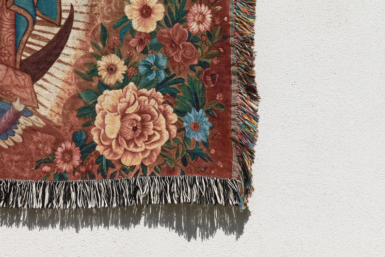 May include: A woven throw blanket with a floral design. The blanket features large peach-colored peonies, blue and yellow flowers, and green leaves against a reddish-brown background. The edge has a fringe of black and white threads.