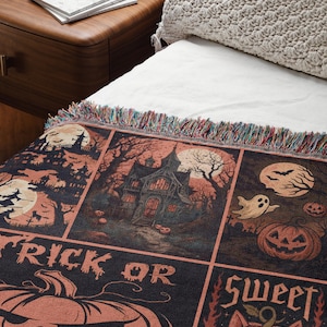 May include: A Halloween-themed throw blanket with a black background and orange and beige illustrations. The design includes haunted houses, pumpkins, bats, ghosts, and the phrases "Trick or Eat" and "Sweet and Spooky". The blanket has a fringed edge.