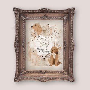 Op de afbeelding: Een ingelijste print met aquarel illustraties van verschillende hondenrassen. Het kunstwerk is gecentreerd rond de zin "Every Dog Needs a Baby". De lijst heeft een sierlijk ontwerp en een bruine afwerking, wat het een vintage uitstraling geeft.