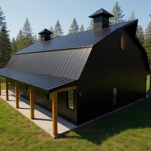 May include: A black barn-style building with a metal roof, two cupolas, and a covered porch supported by wooden posts. The structure features vertical siding, rectangular windows, and an oval window on the upper gable end, set in a grassy area.
