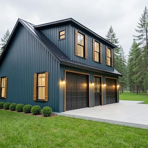May include: A two-story, dark teal-colored building with a black roof and garage doors. The building has wooden shutters and trim, and is surrounded by green grass and tall pine trees. The building has two garage doors and a door.