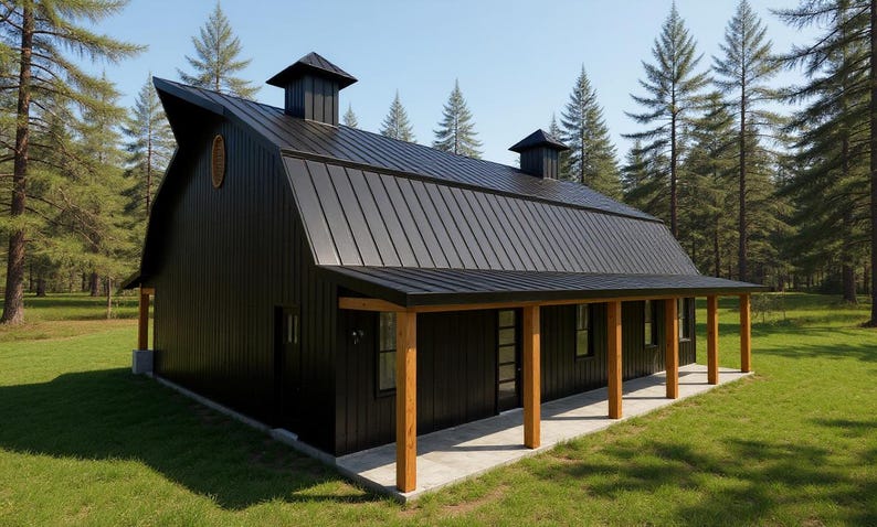 May include: A black barn-style building with a metal roof, two cupolas, and a covered porch supported by natural wood posts. The structure features vertical siding, a glass-paneled door, and a small oval window on the side, set in a grassy area.