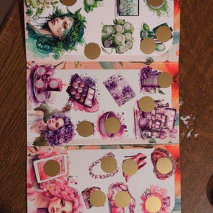 Könnte beinhalten: Ein dekoratives Papierblatt mit Aquarellillustrationen von Schönheitsprodukten und Frauenporträts. Die Illustrationen umfassen Parfümflaschen, Make-up, Schmuck und High Heels. Goldfolienkreise sind über einigen der Bilder platziert.